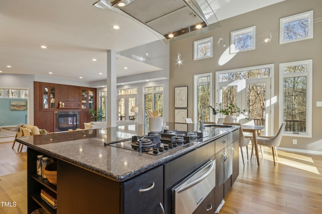 kitchen with french doors, a large island, stainless steel gas cooktop, dark stone countertops, and sink