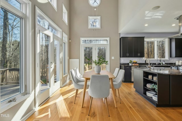 dining space featuring a high ceiling, french doors, light hardwood / wood-style flooring, and sink