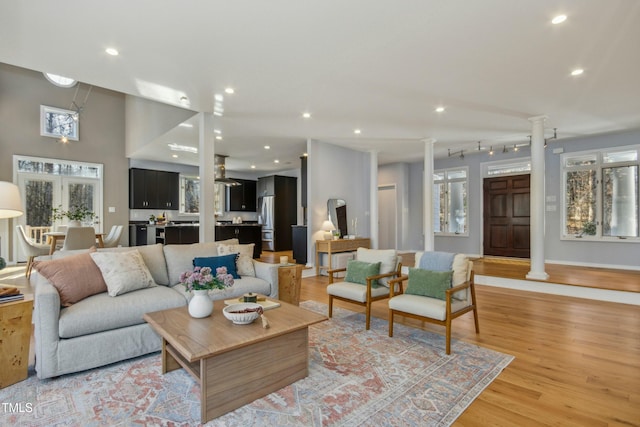 living room with decorative columns and light hardwood / wood-style floors