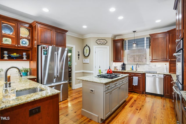 kitchen featuring stainless steel appliances, a sink, light wood finished floors, and ornamental molding