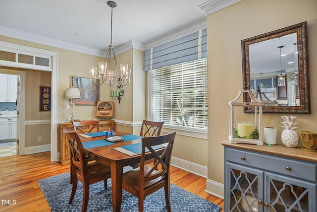 dining area featuring light wood finished floors, baseboards, a chandelier, and crown molding