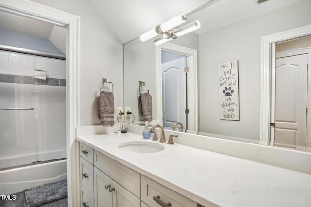 bathroom with vaulted ceiling, visible vents, shower / bath combination with glass door, and vanity