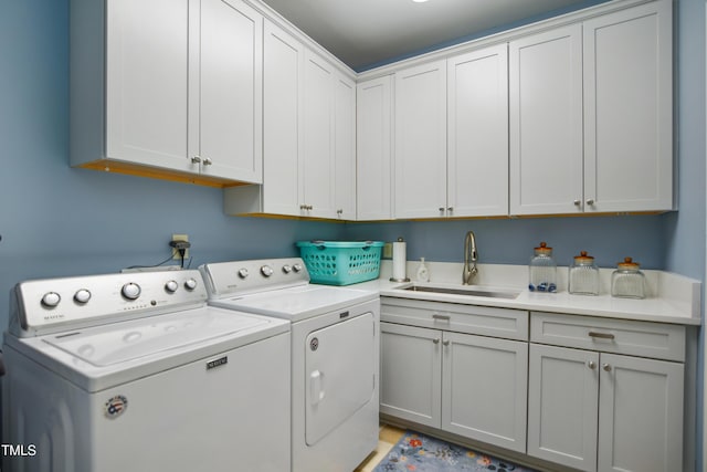 laundry area with cabinet space, washing machine and dryer, and a sink