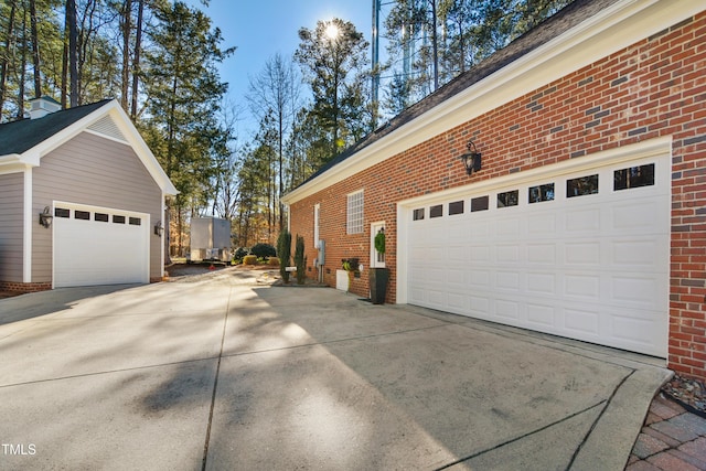 view of side of property featuring a garage, driveway, and brick siding