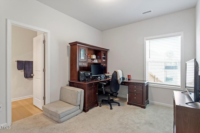 home office with baseboards, visible vents, and light colored carpet