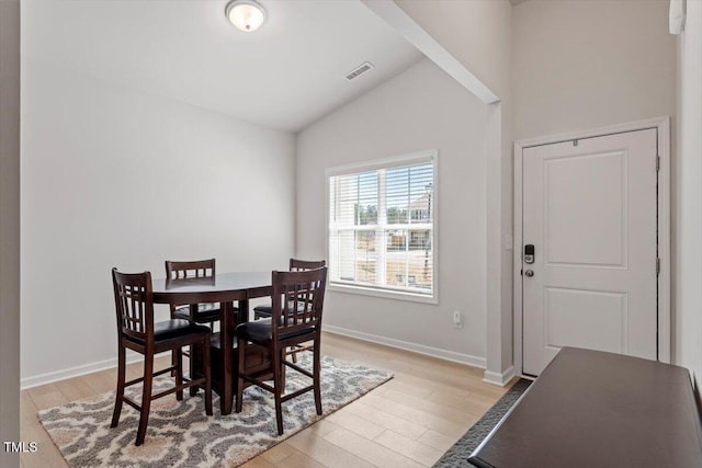 dining room with vaulted ceiling, light wood-type flooring, visible vents, and baseboards