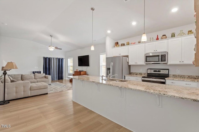 kitchen featuring stainless steel appliances, a breakfast bar, white cabinetry, and light wood-style floors