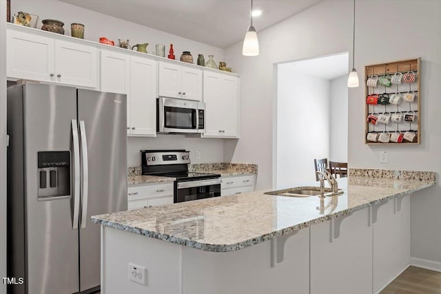 kitchen featuring a breakfast bar, appliances with stainless steel finishes, white cabinetry, a sink, and a peninsula