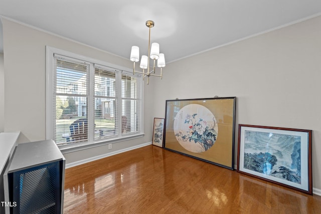 interior space with hardwood / wood-style flooring, ornamental molding, and an inviting chandelier