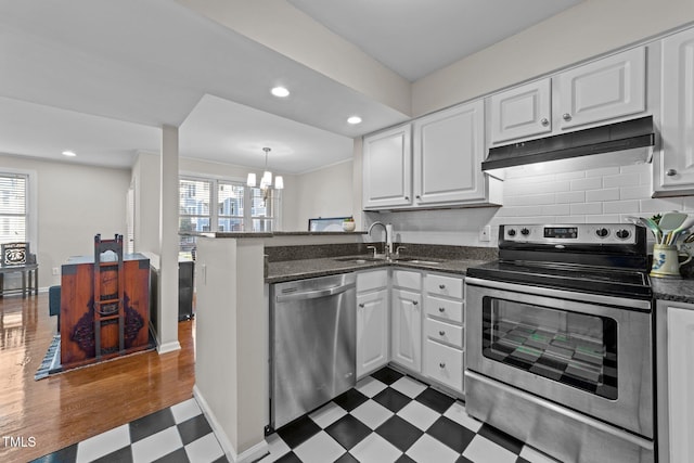 kitchen with appliances with stainless steel finishes, a wealth of natural light, white cabinets, and kitchen peninsula