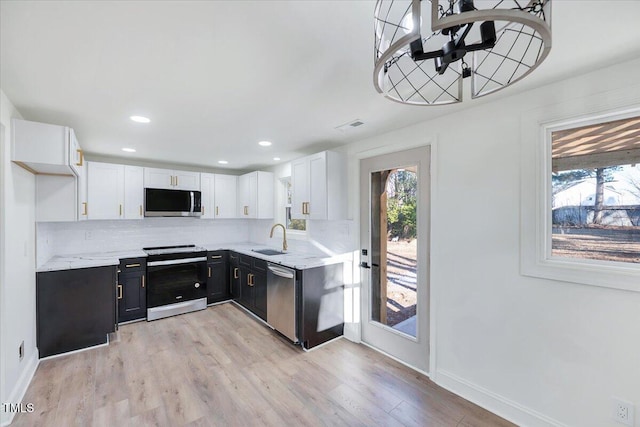 kitchen with appliances with stainless steel finishes, backsplash, white cabinets, light hardwood / wood-style flooring, and sink