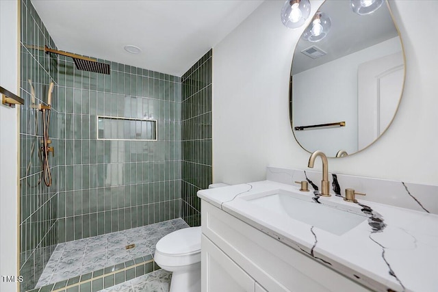 bathroom featuring toilet, vanity, and a tile shower