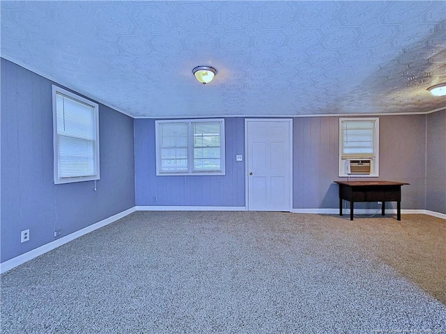 carpeted empty room with cooling unit, a textured ceiling, and wooden walls