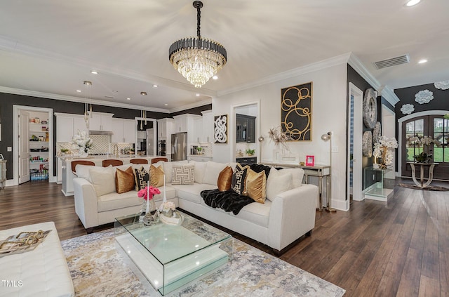 living room with dark hardwood / wood-style flooring, an inviting chandelier, and ornamental molding