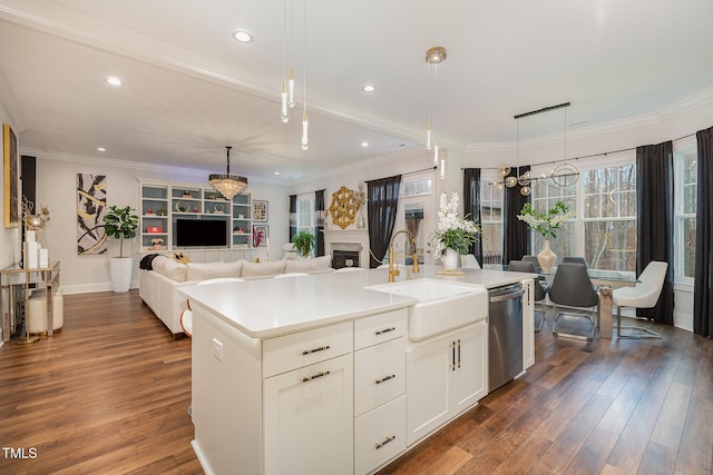 kitchen with dark wood-type flooring, an island with sink, sink, hanging light fixtures, and stainless steel dishwasher