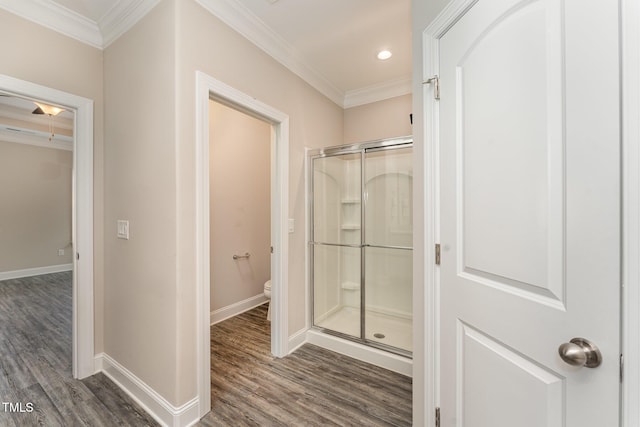 bathroom with hardwood / wood-style floors, walk in shower, toilet, and ornamental molding