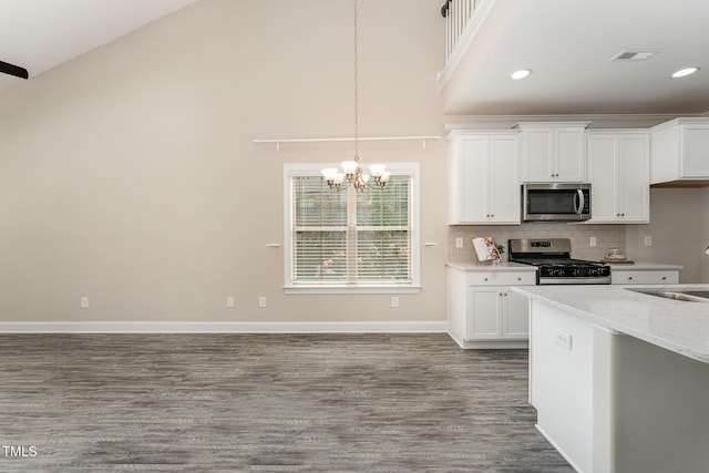 kitchen with stainless steel appliances, decorative light fixtures, white cabinetry, wood-type flooring, and light stone countertops