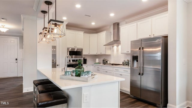 kitchen with white cabinets, decorative light fixtures, wall chimney range hood, and appliances with stainless steel finishes