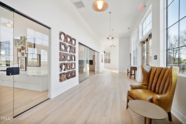 hall with light hardwood / wood-style floors and a high ceiling