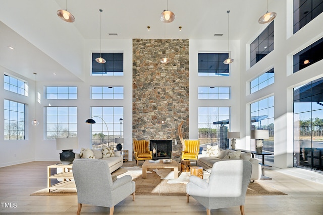 living room with a fireplace, a high ceiling, and light hardwood / wood-style floors