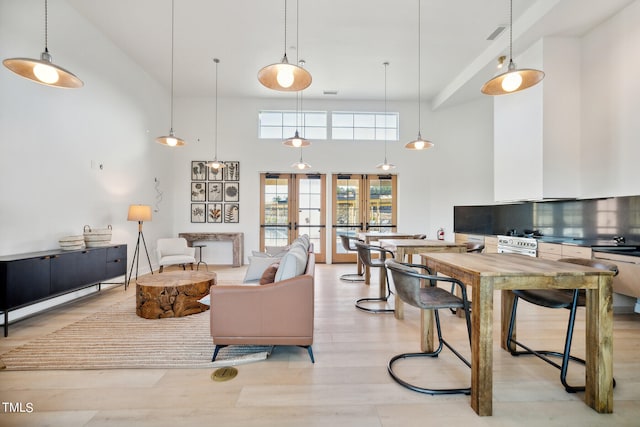 living room featuring french doors, a towering ceiling, and light hardwood / wood-style floors