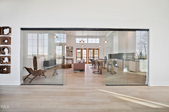 living room featuring french doors, light hardwood / wood-style floors, and a high ceiling