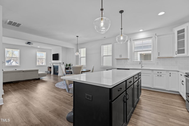 kitchen featuring sink, a center island, light wood-type flooring, pendant lighting, and white cabinets