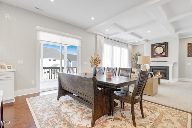 dining space with a healthy amount of sunlight, wood-type flooring, beamed ceiling, and coffered ceiling