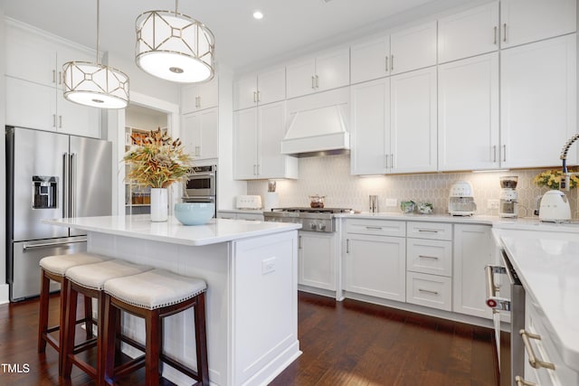 kitchen featuring custom exhaust hood, decorative light fixtures, white cabinetry, stainless steel appliances, and tasteful backsplash