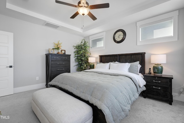 bedroom featuring ceiling fan, light colored carpet, and a raised ceiling