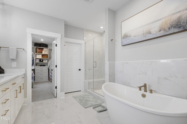 bathroom with plus walk in shower, tile walls, and vanity