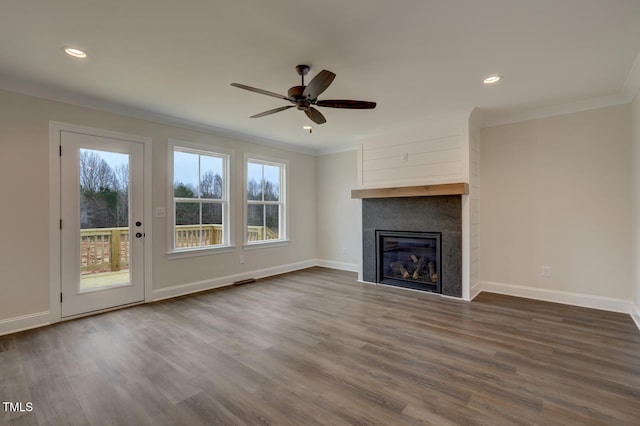 unfurnished living room featuring wood-type flooring, a large fireplace, ceiling fan, and crown molding