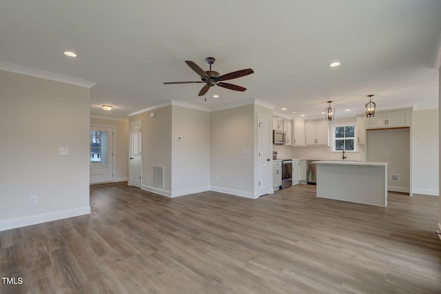 unfurnished living room featuring sink, crown molding, light hardwood / wood-style flooring, and ceiling fan