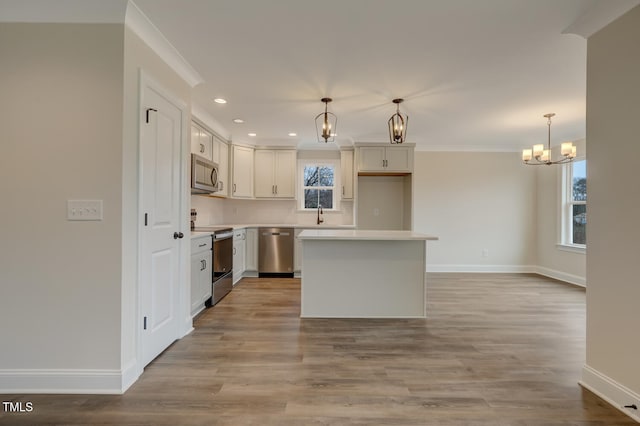 kitchen with stainless steel appliances, a kitchen island, hanging light fixtures, and a notable chandelier