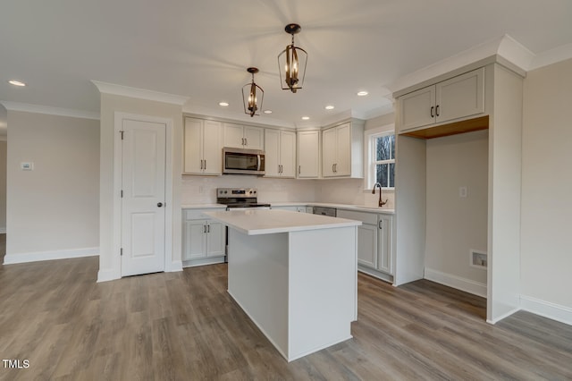 kitchen featuring pendant lighting, sink, stainless steel appliances, a center island, and light wood-type flooring