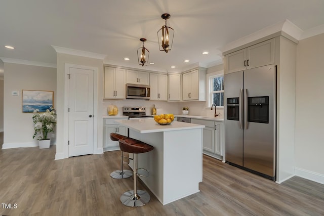 kitchen featuring sink, a breakfast bar area, a kitchen island, pendant lighting, and stainless steel appliances