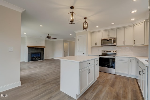 kitchen featuring pendant lighting, white cabinetry, stainless steel appliances, a fireplace, and ceiling fan with notable chandelier