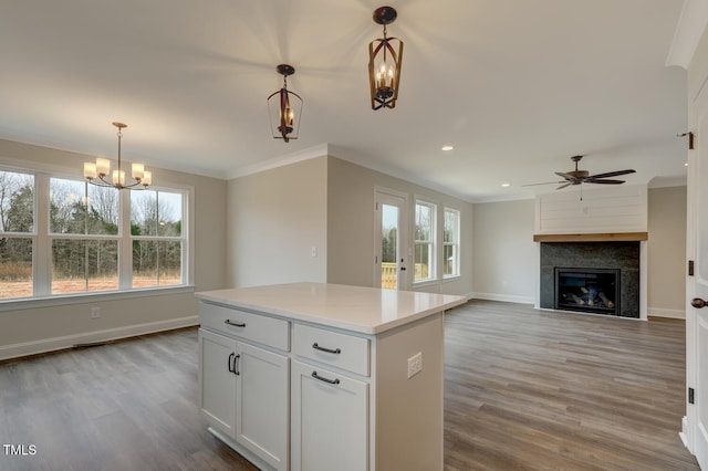 kitchen featuring white cabinetry, a large fireplace, decorative light fixtures, and crown molding