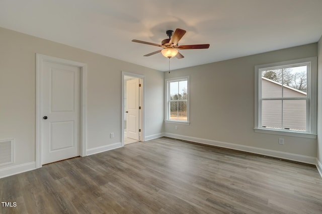 empty room with ceiling fan, plenty of natural light, and light hardwood / wood-style floors