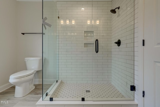 bathroom featuring a shower with door and toilet