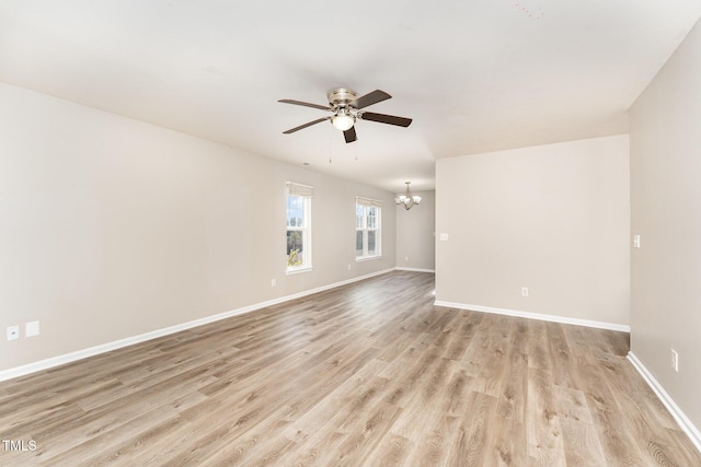 unfurnished room with ceiling fan with notable chandelier and light hardwood / wood-style flooring