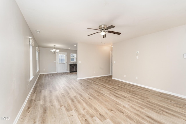 unfurnished room with ceiling fan with notable chandelier and light hardwood / wood-style floors