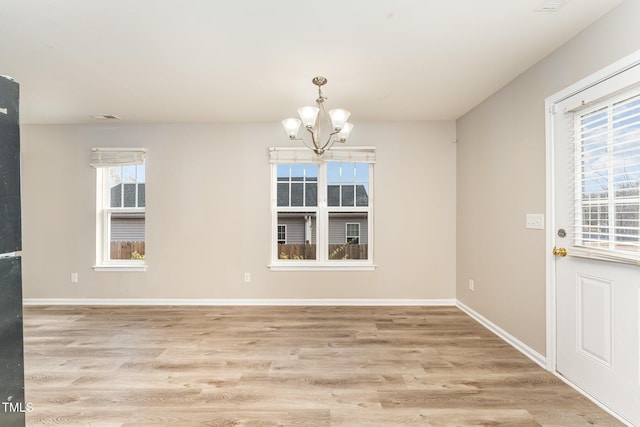 unfurnished dining area with light wood-type flooring and an inviting chandelier