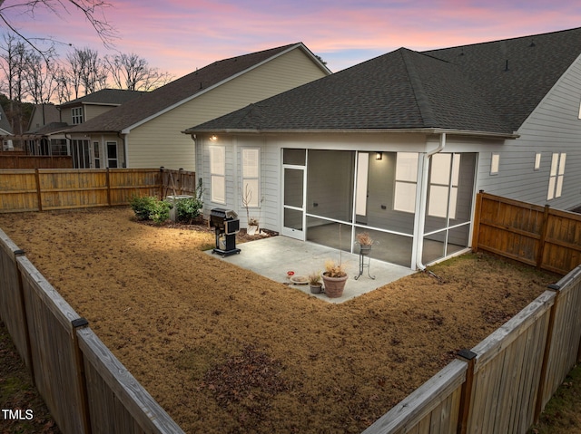 back house at dusk with a patio area and a sunroom