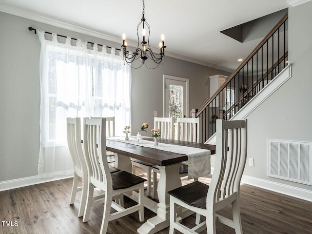 dining space with hardwood / wood-style flooring, crown molding, and a notable chandelier