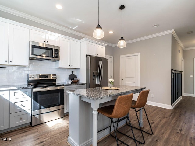 kitchen with dark wood-type flooring, white cabinets, stainless steel appliances, and a center island