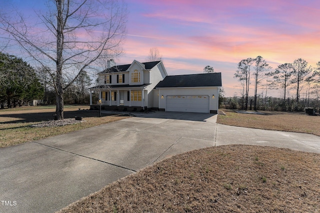 view of front facade with covered porch, a garage, and a lawn