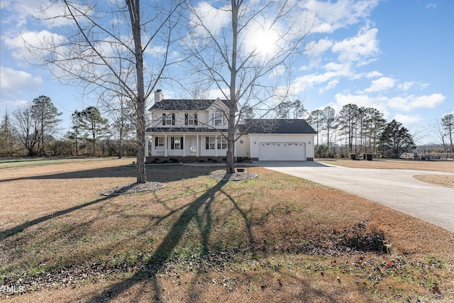 view of front of house featuring covered porch, a garage, and a front lawn