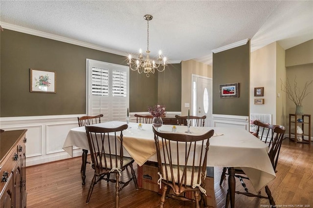 dining space featuring a chandelier, a textured ceiling, and ornamental molding