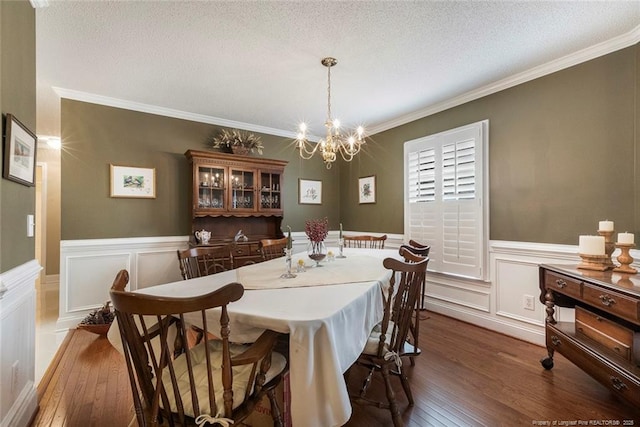 dining space featuring a notable chandelier, dark hardwood / wood-style flooring, a textured ceiling, and ornamental molding